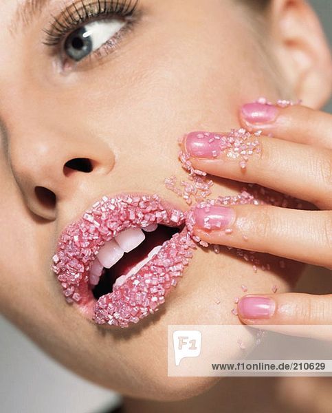 Frau mit rosa Zuckerkristallen auf den Lippen