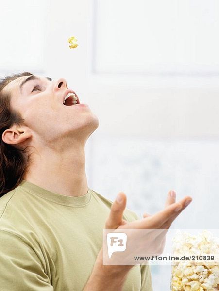 Junger Mann isst Popcorn