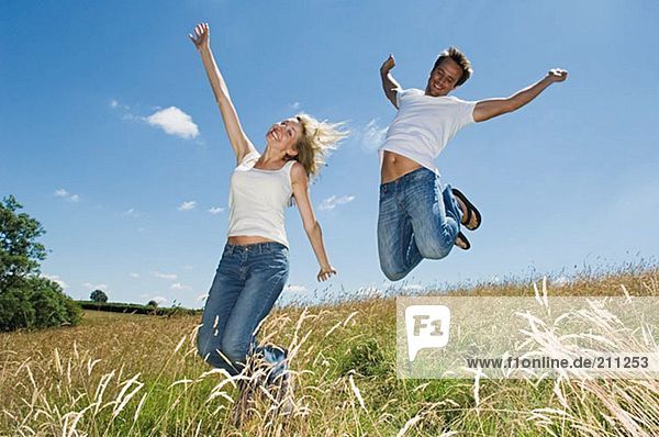 Couple jumping in a field