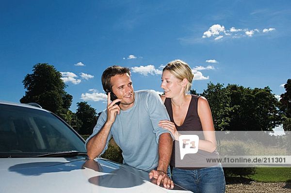 Couple by car using mobile phone