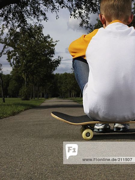 Junge auf einem Skateboard sitzend