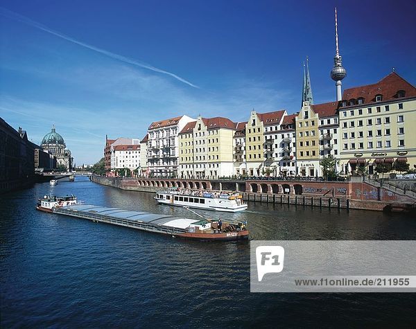 Freighter sailing on river in front of buildings in city  River Spree  Nicolaiviertel  Berlin  Germany