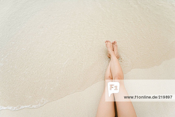 Legs of woman reclining on beach