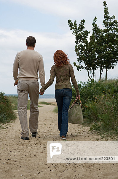 Couple walking toward sandy beach