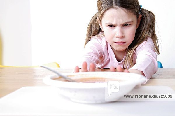 Nahaufnahme eines Mädchens treibt einen Teller Suppe auf dem Tisch