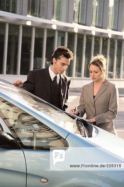 Kaufmann und geschäftsfrau Blick auf Dokument in der Nähe von Auto