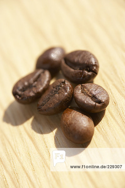 Sechs Kaffebohnen auf einer Holzplatte