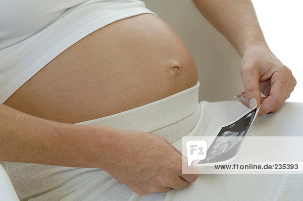 Schwangere Mutter beim Betrachten des Sonogramms des Babys  Mittelteil