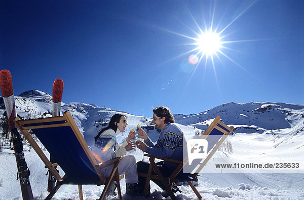 Paar sitzend auf Liegestuhl in Schneerösterbrille  Seitenansicht