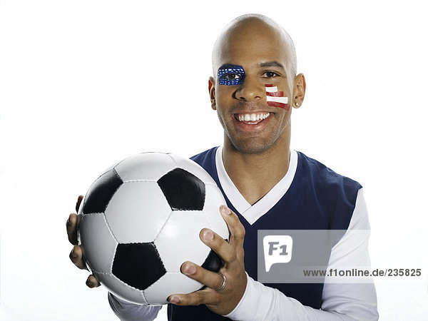 Mann mit USA-Flagge auf Gesicht gemalt  hält Fußball