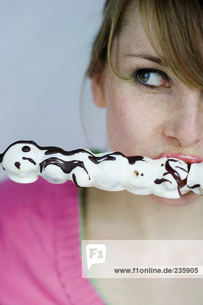 Young woman eating chocolate sweet  looking to side