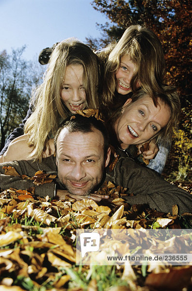 Familie auf Herbstblättern liegend,  Nahaufnahme,  Portrait