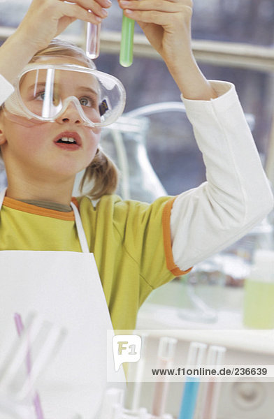 Girl (8-9) wearing protective goggles  holding test tube