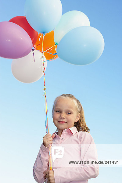 Junges Mädchen mit einem Haufen Luftballons