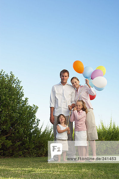 Porträt der Familie stand im Garten mit Luftballons