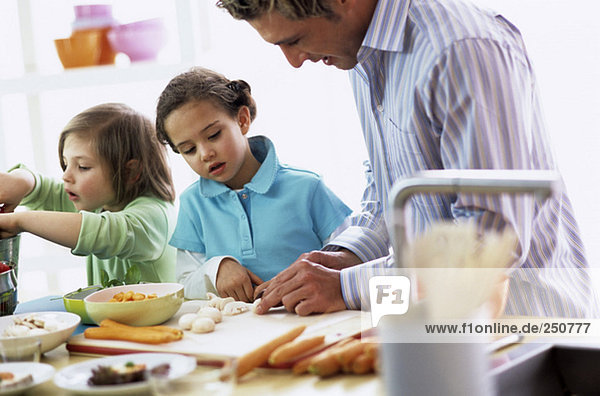 Vater mit Kindern (4-7) beim Zubereiten des Essens