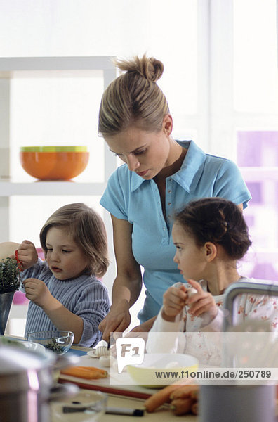 Mother and two children preparing meal in kitchen