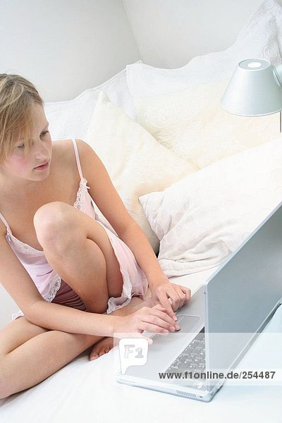 Teenage girl using a laptop in bed