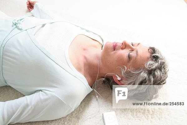 High angle view of senior woman listening to MP3 player
