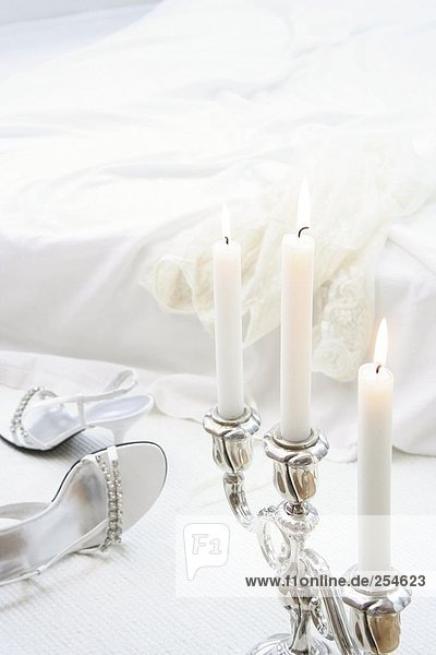 Close-up of lit candles with pair of high heels in background
