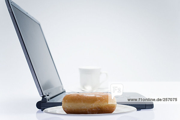 Kaffee und Doughnut am Laptop