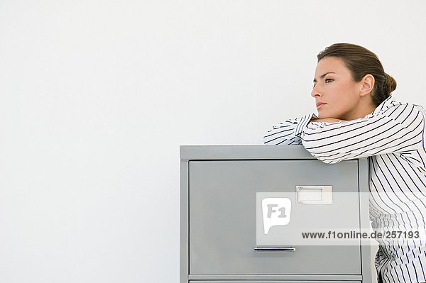 Businesswoman leaning on a filing cabinet