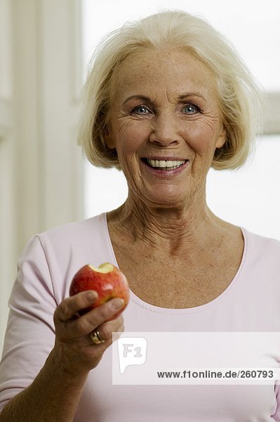 Seniorin beim Apfelessen  lächelnd  Nahaufnahme  Portrait