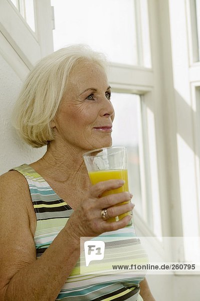 Seniorin mit einem Glas Saft  lächelnd  Nahaufnahme
