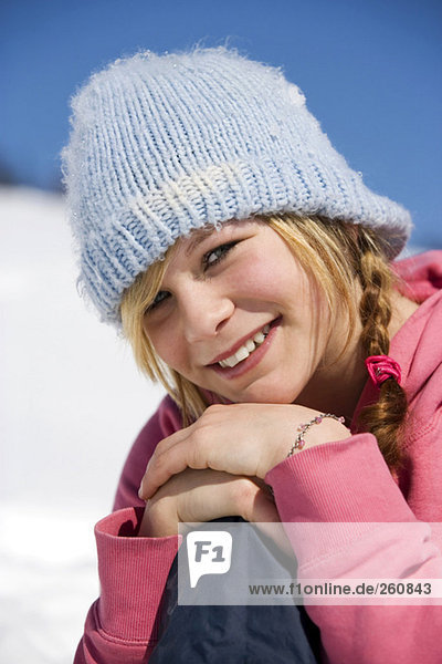 Österreich  Mädchen (10-11) im Schnee sitzend  lächelnd  Nahaufnahme  Portrait