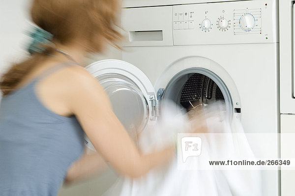 Frau entleert Waschmaschine