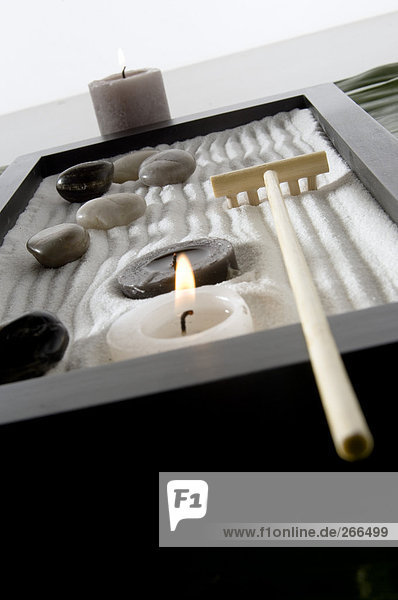 Kerzen und Peebles auf weißem Sand