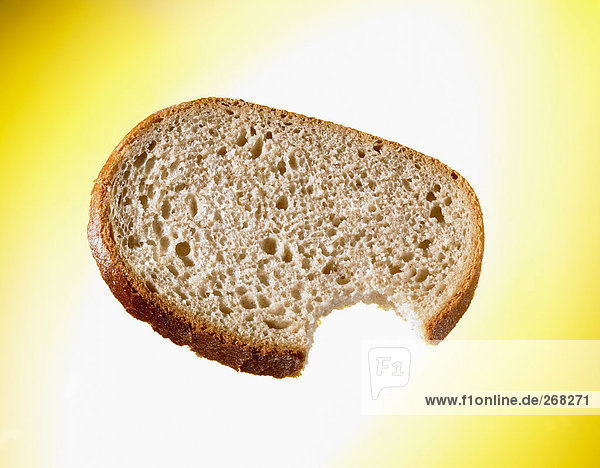 Angebissene Brotscheibe vor gelbem Hintergrund