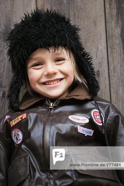 Bildnis eines Knaben lächelnd gekleidet in einem Leder-Jacke und Mütze.