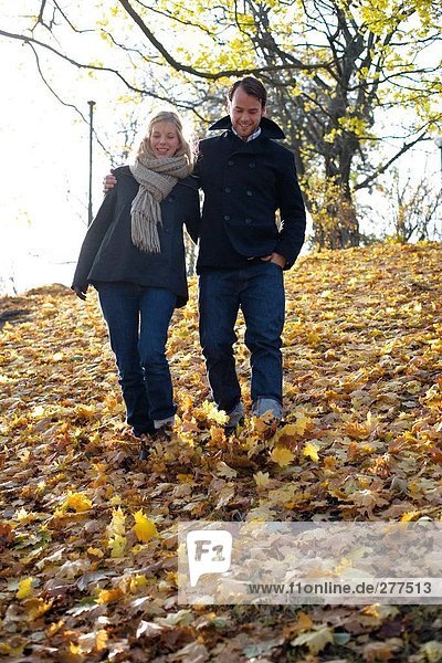 A couple on a walk among autumn leaves.