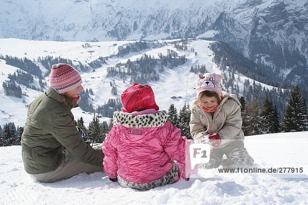 Frau und ihre Kinder spielen im Schnee