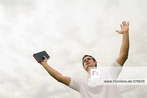 Man holding the bible with arms raised