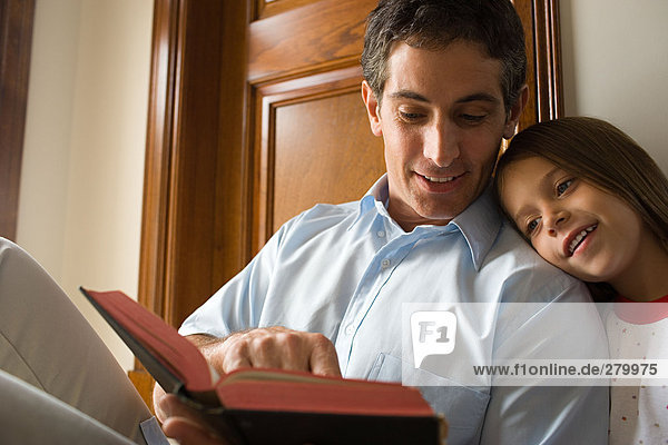 Father reading bible with daughter