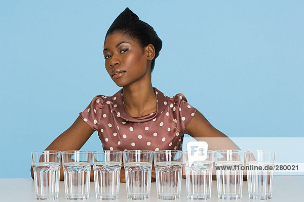 Junge Frau mit acht Gläsern Wasser