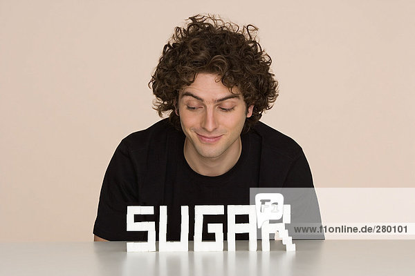 Junger Mann mit Zucker auf einem Tisch