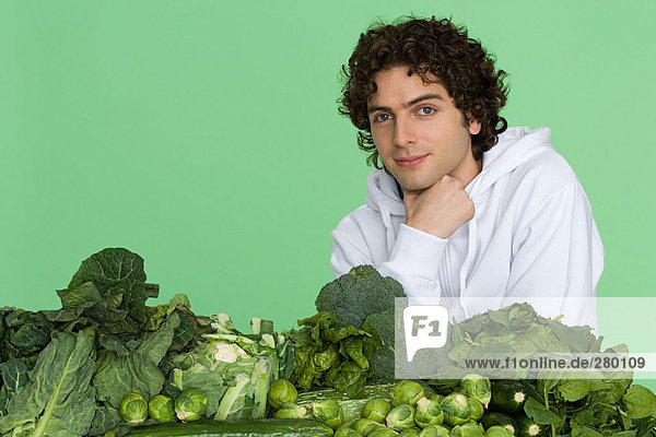 Junger Mann mit Gemüsehaufen
