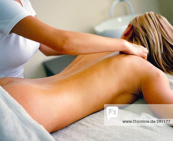 Rückansicht des nackte junge Frau immer wieder Massage von Massage-Therapeut