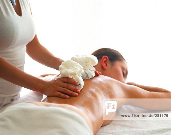 Rückansicht des nackte junge Frau immer Erwärmung-Stone-Massage von Massage-Therapeut
