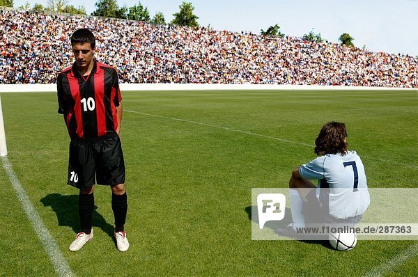 Two soccer players waiting on pitch