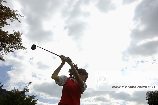 Eine Frau in Aktion von der Durchschwung mit Golf club