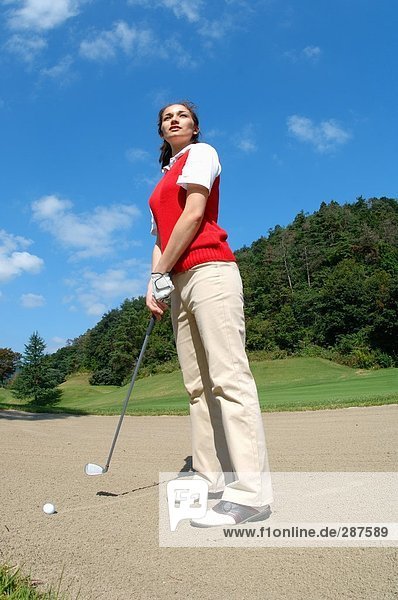 Woman contemplating before playing a bunker shot