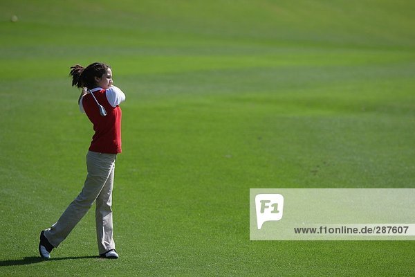 Young woman making a stroke with a golf club