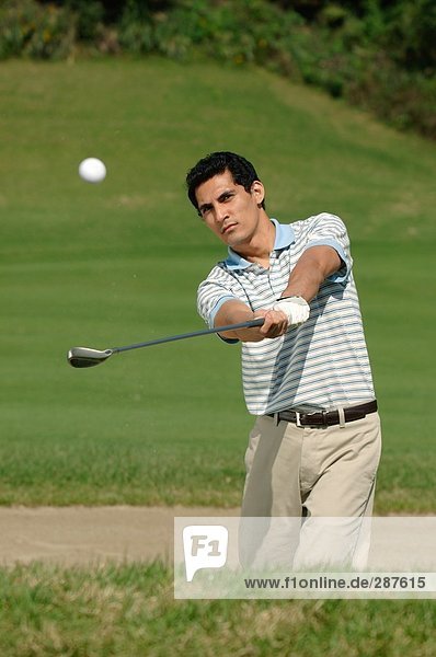 Front view of a man playing a bunker shot