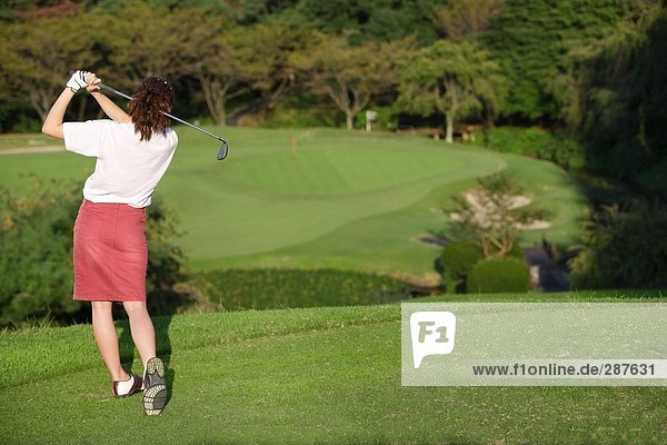 Rear view of a woman teeing off on a short hole