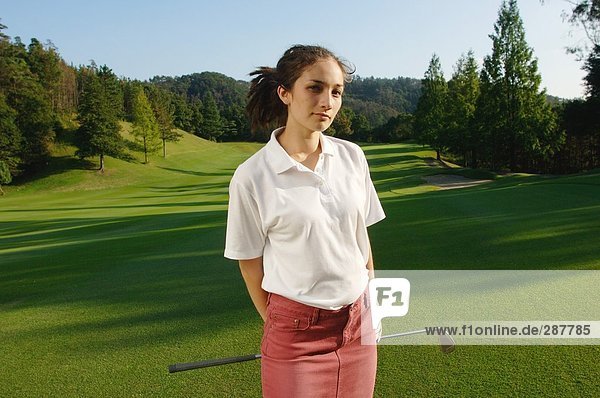 Frau vor die Kamera mit einem Golfplatz erstreckt sich hinter