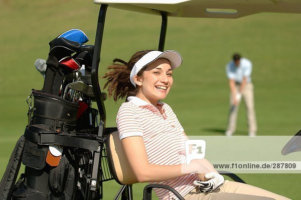 Frau Lächeln in die Kamera von ihr Golf-Karre